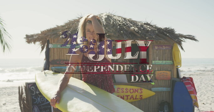 American flag waving over independence day text against caucasian woman with surfboard on the beach - Powered by Adobe