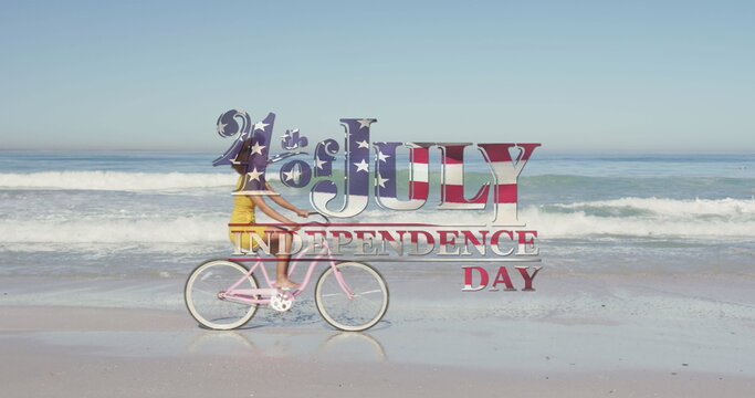 American flag waving over independence day text against woman riding bicycle on the beach - Powered by Adobe