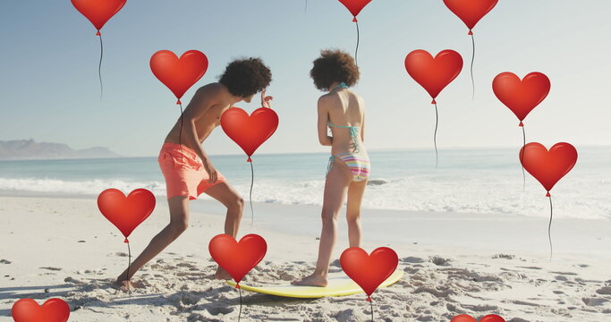 Image of heart icons over couple with surfboard on beach - Powered by Adobe