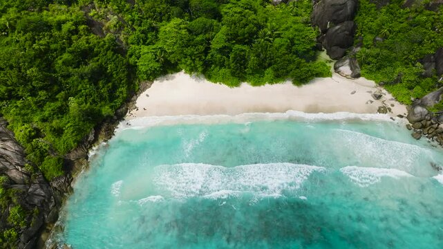 Idyllic beach surrounded by verdant hills and blue waters. Seychelles. Anse Du Riz beach. Baie Ternay Marine National Park.