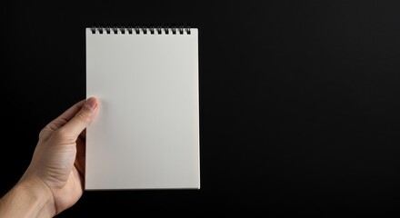 Obraz premium Blank spiral notebook held in hand.