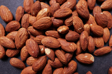 A pile of almonds on a black surface