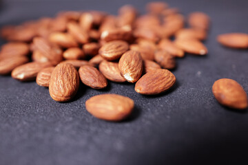 A pile of almonds on a black surface