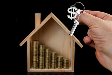 Symbolic wooden house, gold coins and apartment key with dollar symbol keychain