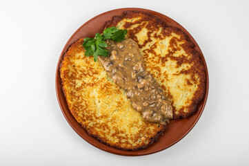 Golden brown potato pancake with sour cream and fresh parsley on a rustic clay plate. Traditional Eastern European dish, crispy texture and exquisite homemade taste, homemade dish