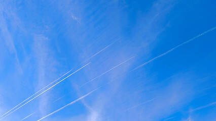 blue sky with white aircraft trails