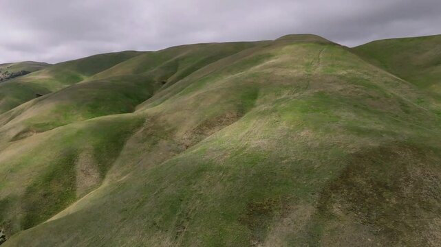 Dappled sunlight and dramatic shadows from fast moving clouds moving over a landscape of rolling hills