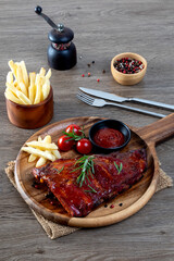 Delicious barbecued ribs seasoned with a spicy basting sauce herbs on wooden chopping board