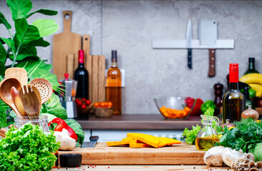 Food background. Healthy eating, cooking, blogging scene. Оak cutting board with pumpkin pieces, mushrooms, lettuce and spices on cozy kitchen with wooden table, kitchenware and utensils
