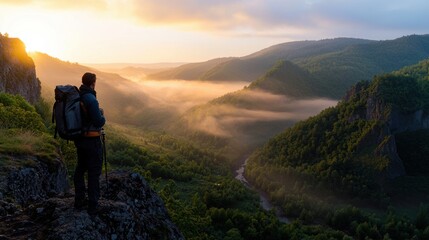 Fototapeta premium Scenic Mountain Landscape with Hiker at Sunrise Overlooking Lush Green Valley and Misty River in Warm Golden Light