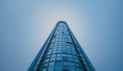 Worm's-eye view of a modern glass skyscraper against a clear blue sky,