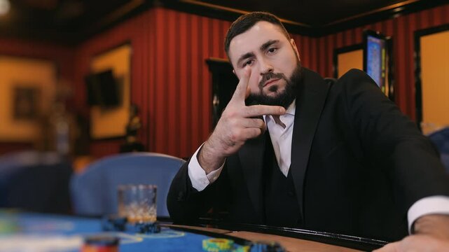 Man in a suit throwing a playing card toward the camera at a casino table.