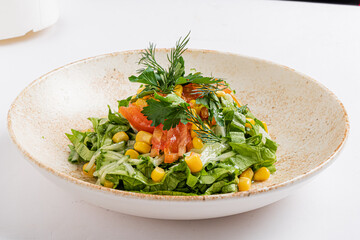 A vibrant garden salad features fresh greens, juicy tomatoes, and sweet corn topped with herbs