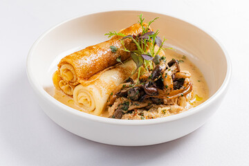 Savory crepes are rolled and served over a rich mushroom sauce, garnished with fresh herbs