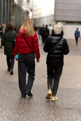 Obraz premium Two women wearing down jackets shopping on a street in Milan.