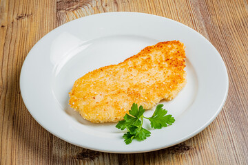 Deliciously crispy fried fish fillet garnished with fresh parsley on a wooden table