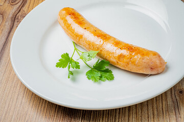 Juicy sausage on a white plate, garnished with vibrant green herbs—inviting and delicious