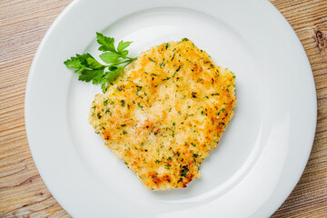 Golden-brown fish fillet is beautifully presented with vibrant parsley for a delicious touch