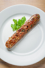 Juicy kebab glistens under soft lighting, accompanied by a green parsley garnish on a white plate