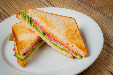 Toasted sandwich features layers of lettuce, tomato, and savory meats, displayed on a plate