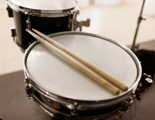 A pair of drumsticks are resting on a drum head