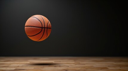 Obraz premium A basketball hovers above a wooden floor, set against a dark background, emphasizing its texture and the sport's dynamic nature.