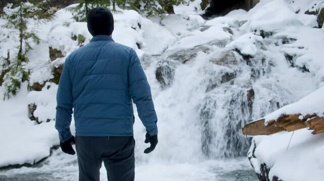 Adventurous Man Hiking to Snowy Waterfall View