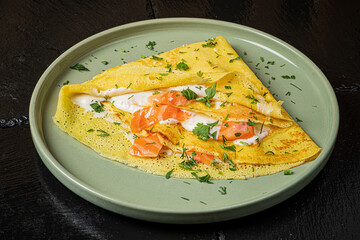 Tasty smoked salmon crepe on a green plate, perfect for breakfast