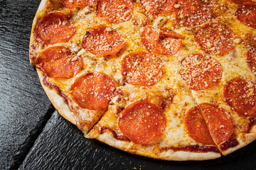 A delicious pizza with pepperoni and gooey cheese on a dark granite surface