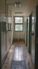 Empty corridor with restroom stalls in abandoned building