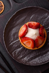 Round sweet tart with strawberry pieces and cream