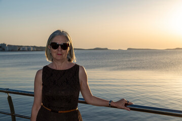 Elegant Woman Enjoying a Serene Sunset by a Calm Waterfront