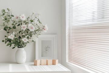 Simple, serene, and bright interior with a vase of flowers, wooden blocks, and a window