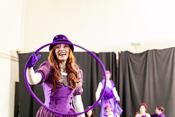 Redhead woman wearing purple costume and hat, spinning plastic hula hoop during circus rehearsal © JoseIMartin