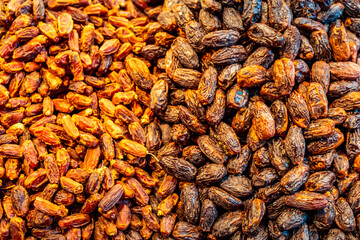 Two varieties of dried dates displayed side by side at a market. A traditional, healthy fruit often eaten to break the fast during Ramadan, rich in nutrients and natural sweetness.