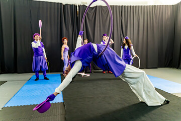 Circus artist hangs upside down from an aerial hoop, performing a captivating acrobatic stunt while...