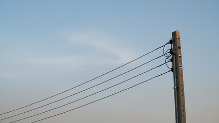 Sky background of soft blue and orange gradient with poles and wires. Electric poles with sunset sky texture background. Clear blue, softness, nature, landscape, and scene concept for texture and web.