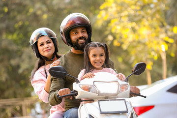 young indian family enjoy riding on scooter wearing helmet while traveling, Parents with young...