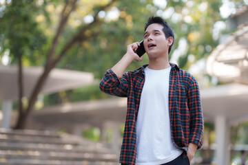 Fototapeta premium Young man talking on smartphone in urban park setting