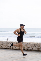 Male athlete running beside sea wall during outdoor workout.