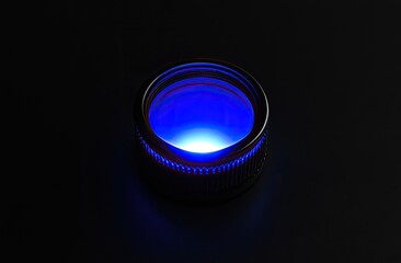 Illuminated circular object with vibrant blue light.  A metallic ring encloses a glowing blue center, creating a striking visual contrast against a dark background