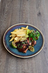 A plated serving of grilled Jamaican jerk chicken steak with crispy French fries and a fresh salad