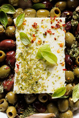 Close up view of feta cheese with mixed olives, olive oil and aromatic herbs 