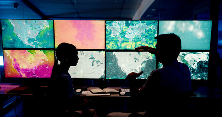 Computer, screen and maps with people in control room for storm tracking, satellite forecast or planning weather pattern. Back, meteorology team or radar data for climate monitor, silhouette or night
