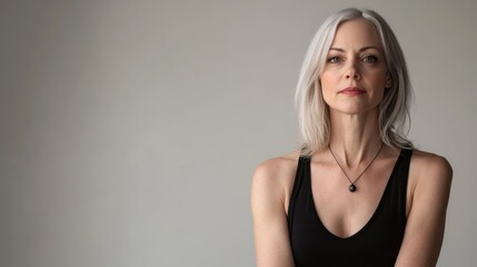 Fototapeta premium Subtle Elegance: A stunning woman with silver hair exudes quiet confidence, her gaze direct and inviting. A portrait that captures inner strength and grace.