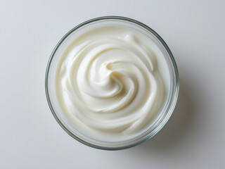 A top-down view of a glass bowl filled with smooth, creamy yogurt. The swirl pattern and soft texture create a visually appealing food presentation, emphasizing freshness and purity.