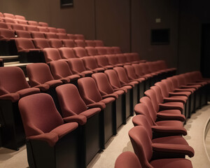 Fototapeta premium rows of maroon auditorium seats arranged in a tiered formation