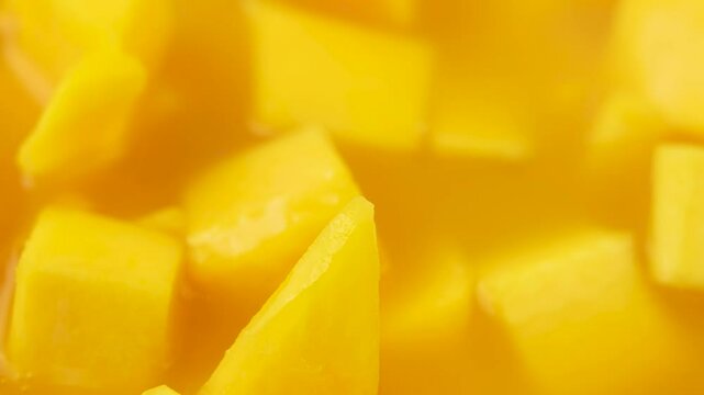 Bowl with chopped yellow mangoes. The fruit is diced. The bowl is filled with yellow juice.
