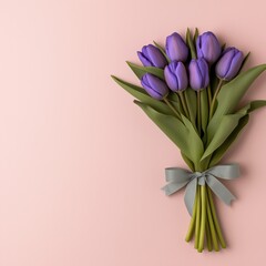 Obraz premium Beautiful deep sapphire-blue tulips elegantly wrapped with a pale seafoam-green ribbon on a dusty rose background with ample copyspace