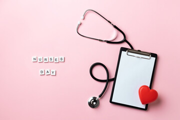 Tablet with doctor stethoscope, red heart and the inscription Nurses Day on pink background. Copy...